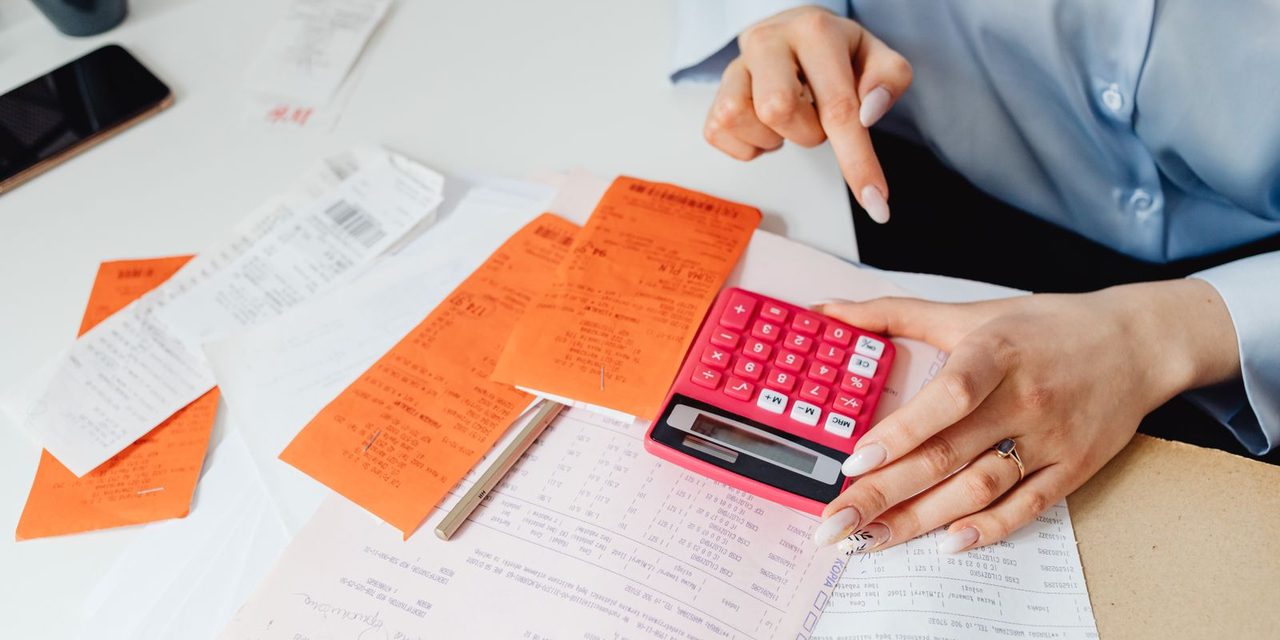 Un dirigeant calcule les charges sociales de son entreprise en Nouvelle-Calédonie sur un bureau avec calculatrice et bulletins de paie