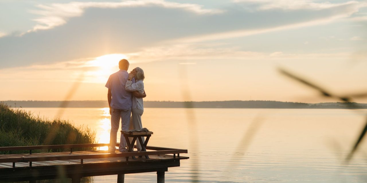 Couple de retraités calédoniens marchant sur une plage au coucher du soleil, illustrant la retraite des salariés en Nouvelle-Calédonie