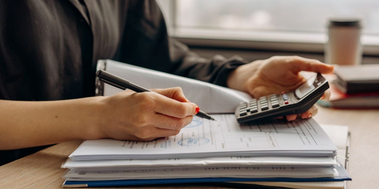 Gestionnaire de paie examinant des bulletins de salaire et des documents administratifs sur un bureau en Nouvelle-Calédonie