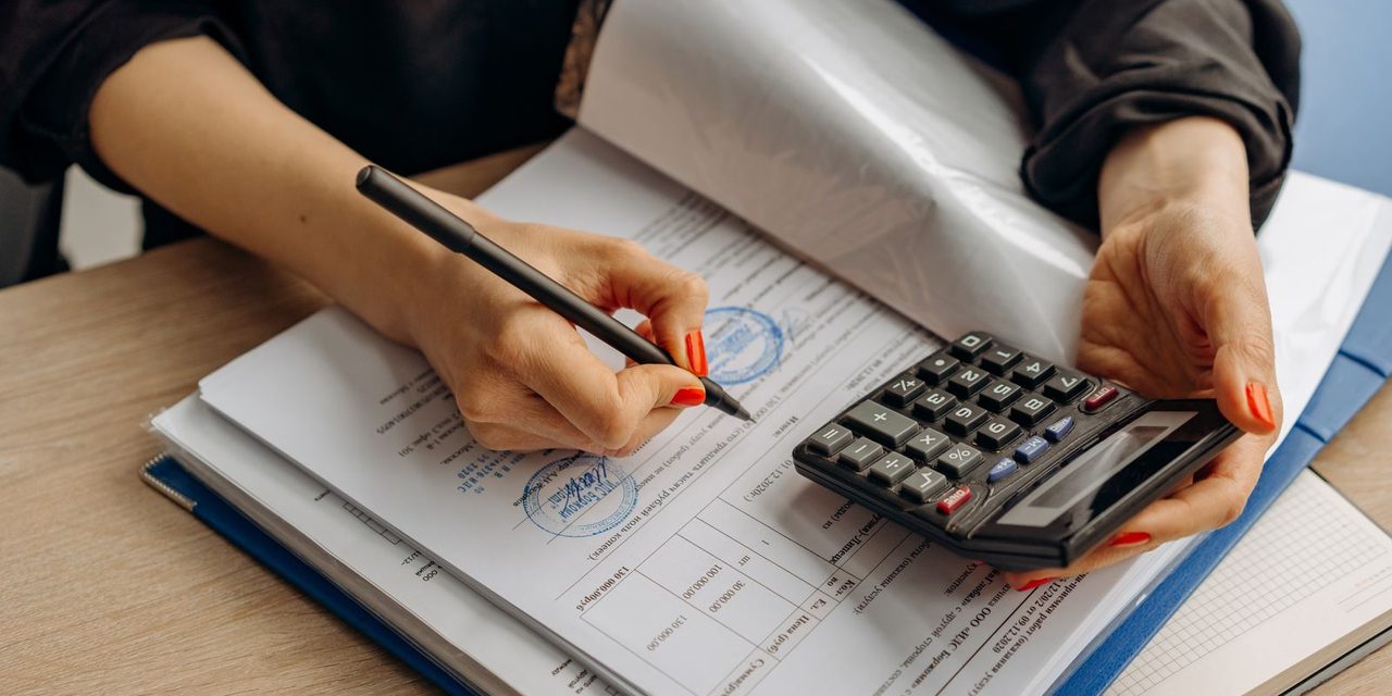 Gestionnaire de paie calédonien vérifiant un bulletin de salaire avec calculatrice et documents sur un bureau à Nouméa